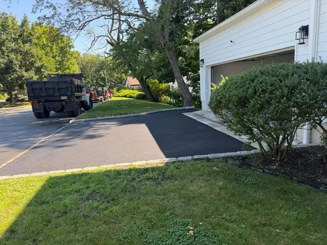 Asphalt driveway framed by granite block curbing beside landscaped beds