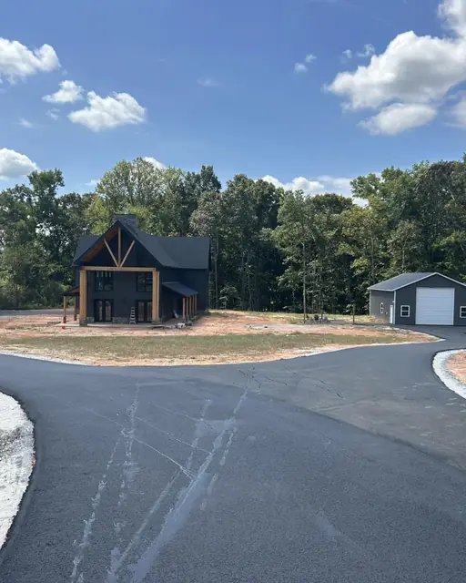 Fresh asphalt driveway leading to a detached garage
