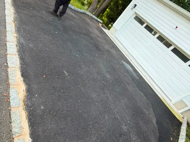 Close view of new asphalt meeting granite curb edging at a garage