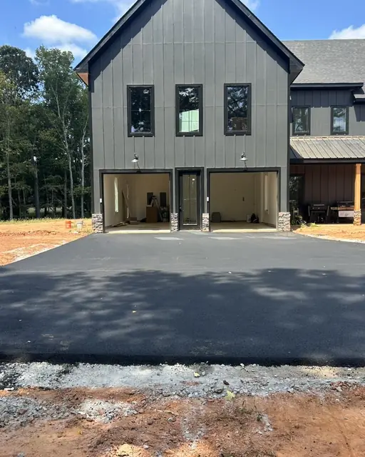 New asphalt driveway in front of a modern farmhouse garage