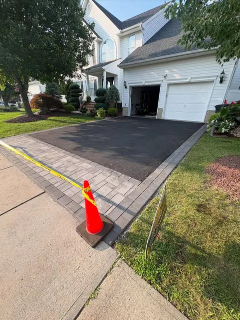 Asphalt driveway with a gray paver border along the walkway