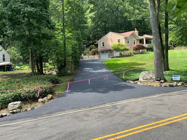 New asphalt driveway joining the street with a clean tie-in at the curb line