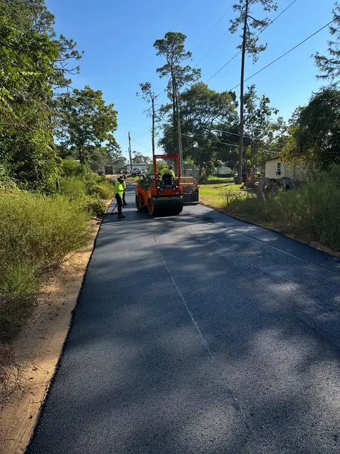 Asphalt paving in progress on a long rural driveway