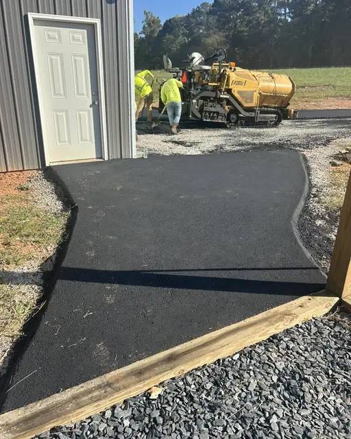 Crew paving an asphalt walkway beside a commercial building