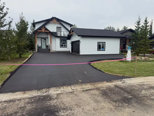 Curved asphalt driveway at a newly built home with a three-car garage
