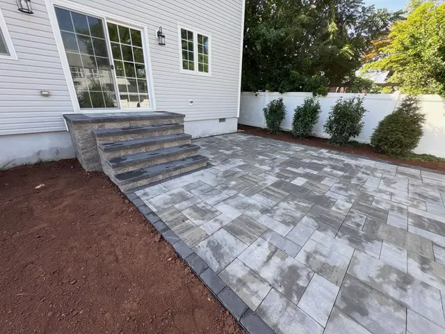 Gray slab paver patio with matching block steps at a back door