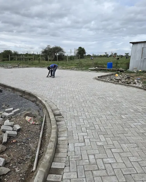 Installer laying a herringbone pattern paver driveway with curved edge restraint