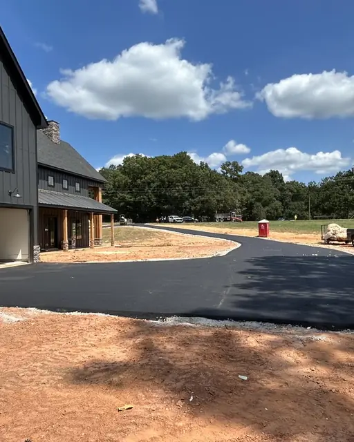New asphalt driveway beside a dark-sided new construction home