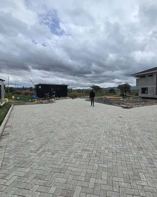 Long paver driveway installation in progress on an open lot