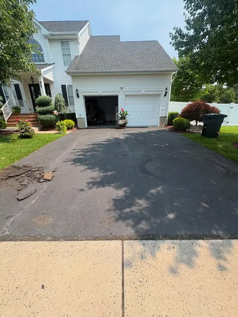 Sealcoated asphalt driveway with an even dark finish at a colonial home